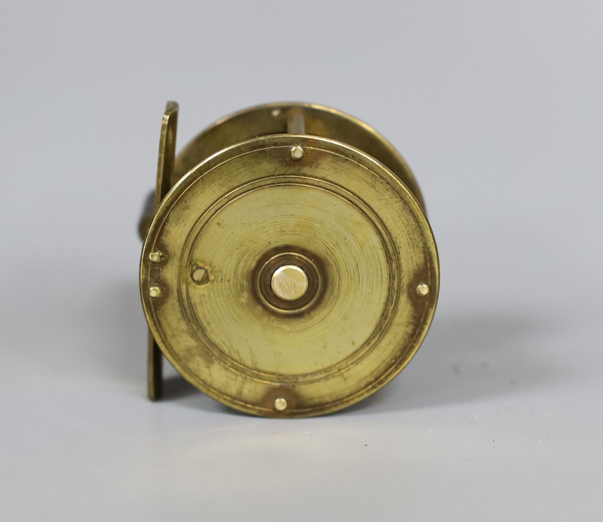 An Allcock brass fishing reel, 6cm. diam., in original box